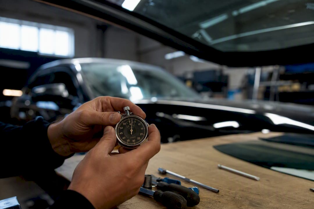 Mains chronométrant le temps de séchage de la colle du pare-brise