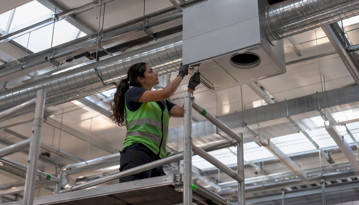 Technician installing mechanical ventilation ducts