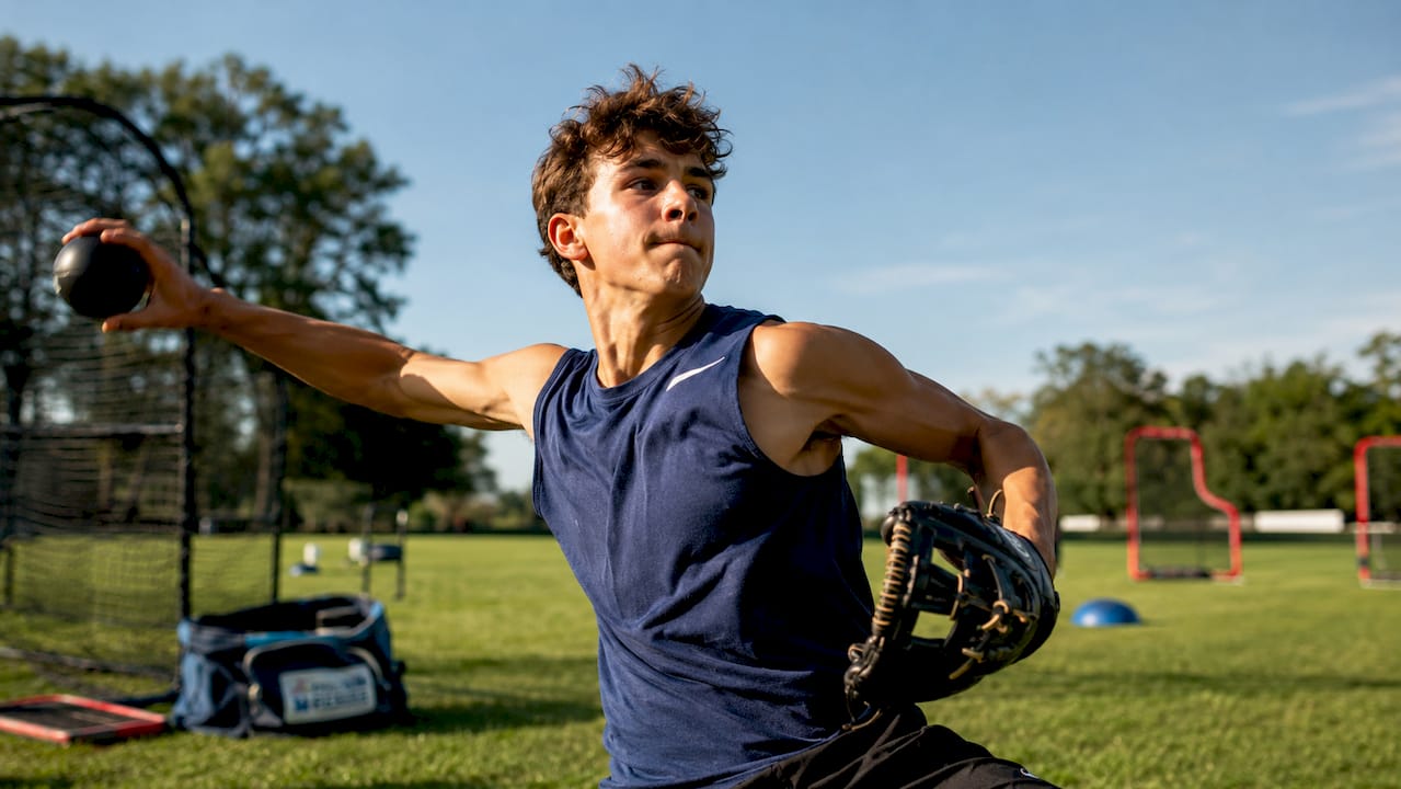Teen baseball player throwing weighted ball indoors