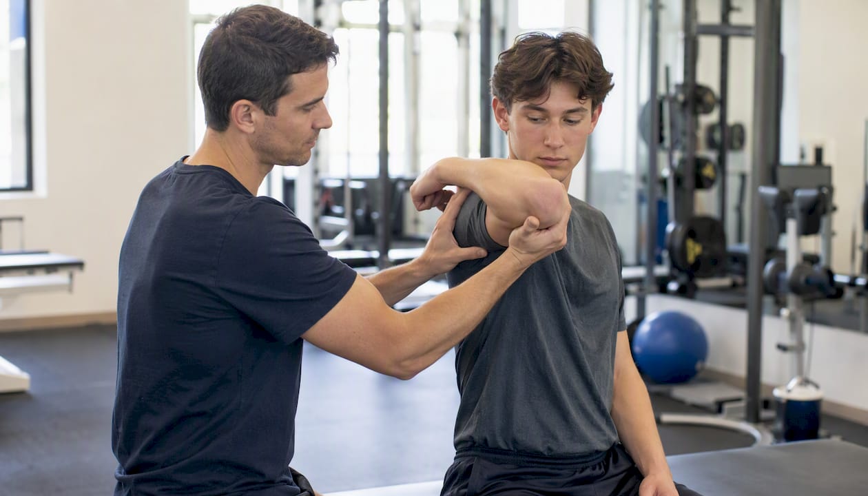 Physical therapist assisting youth athlete stretch arm