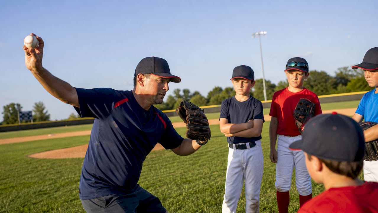 Coach demonstrating pitching mechanics outdoors