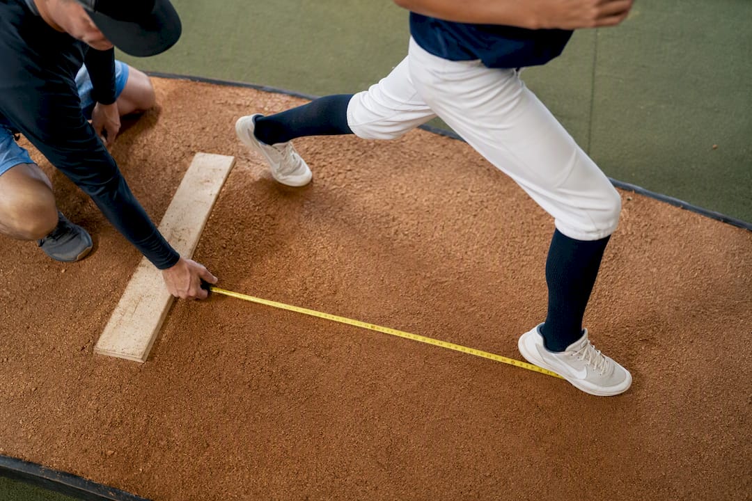 Coach measuring pitcher stride from rubber