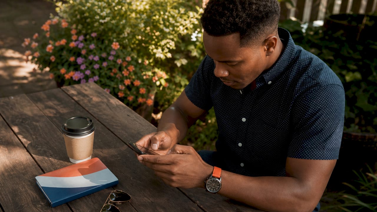 Owner sending guest message outdoors at café table
