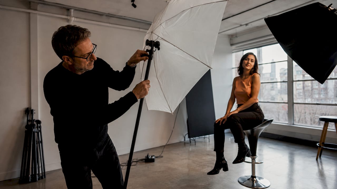 Photographer adjusting umbrella reflector during portrait shoot