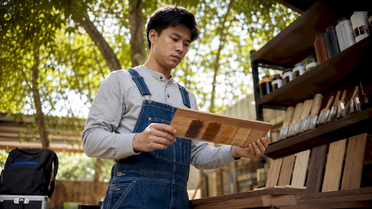 Technician examining stained hardwood sample plank