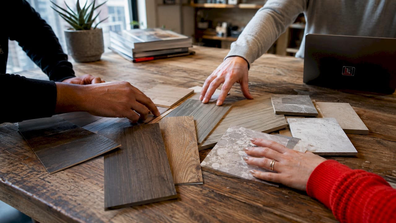 Hands selecting flooring material samples on table