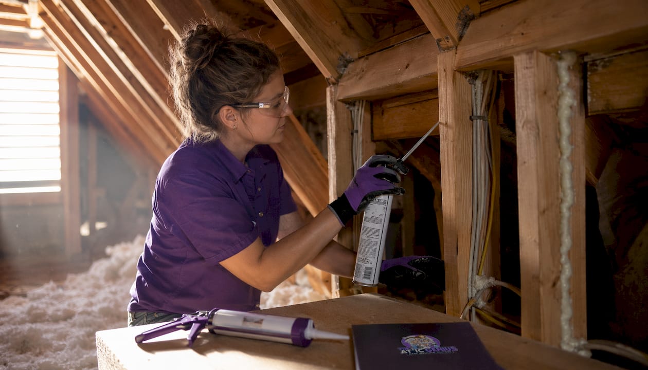 Close-up hands sealing attic air leaks