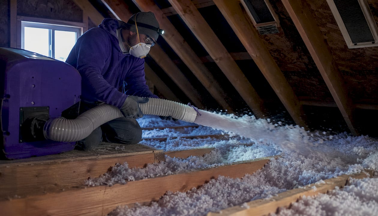 Technician installing blown-in attic insulation