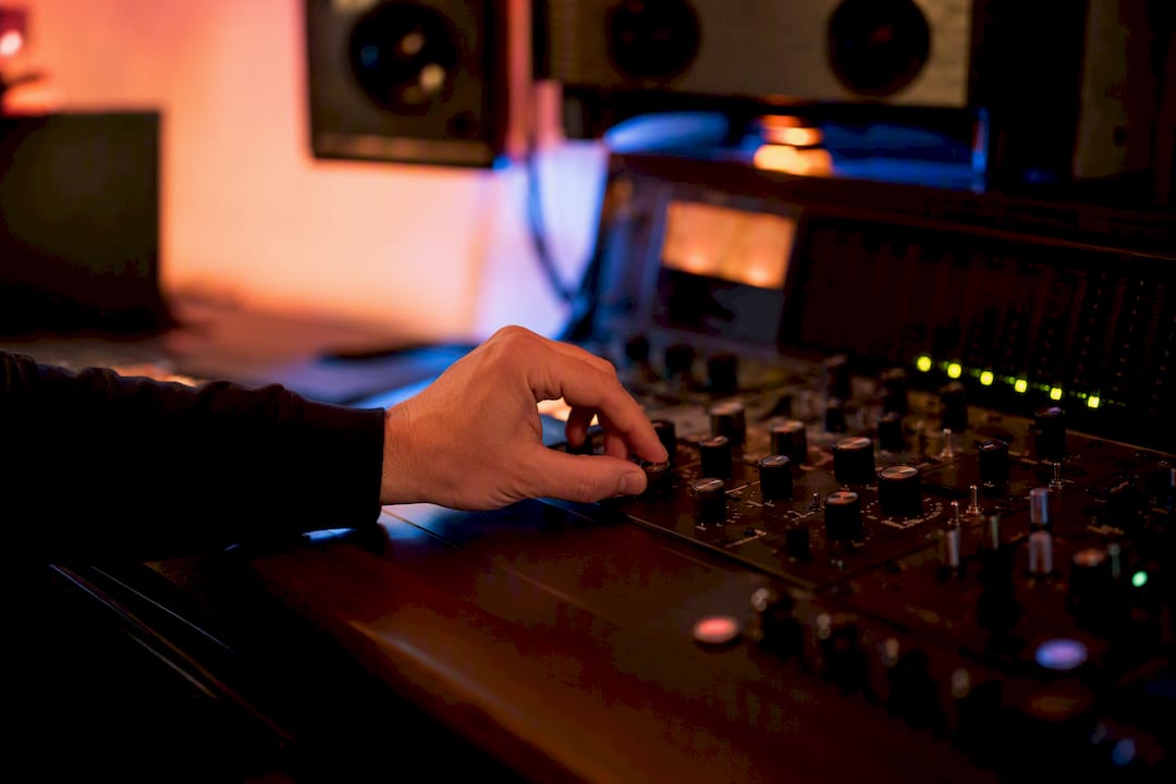 Hands adjusting dither control on mastering console
