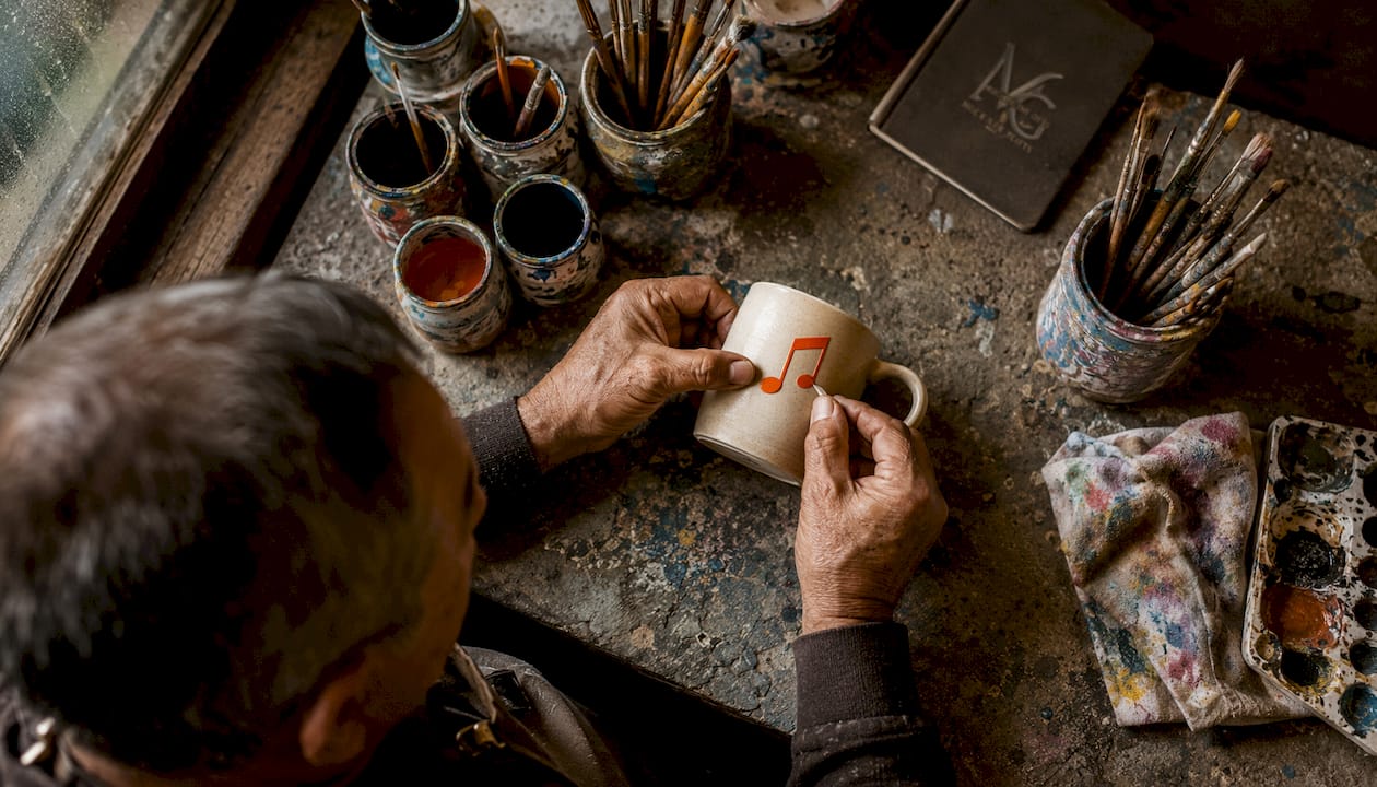 Craftsman applying music decal on mug
