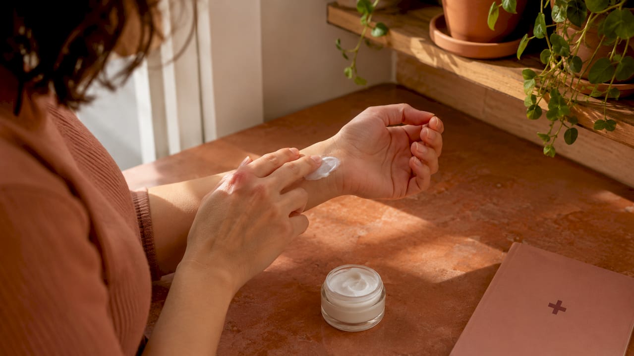 Hands applying serum over bathroom sink