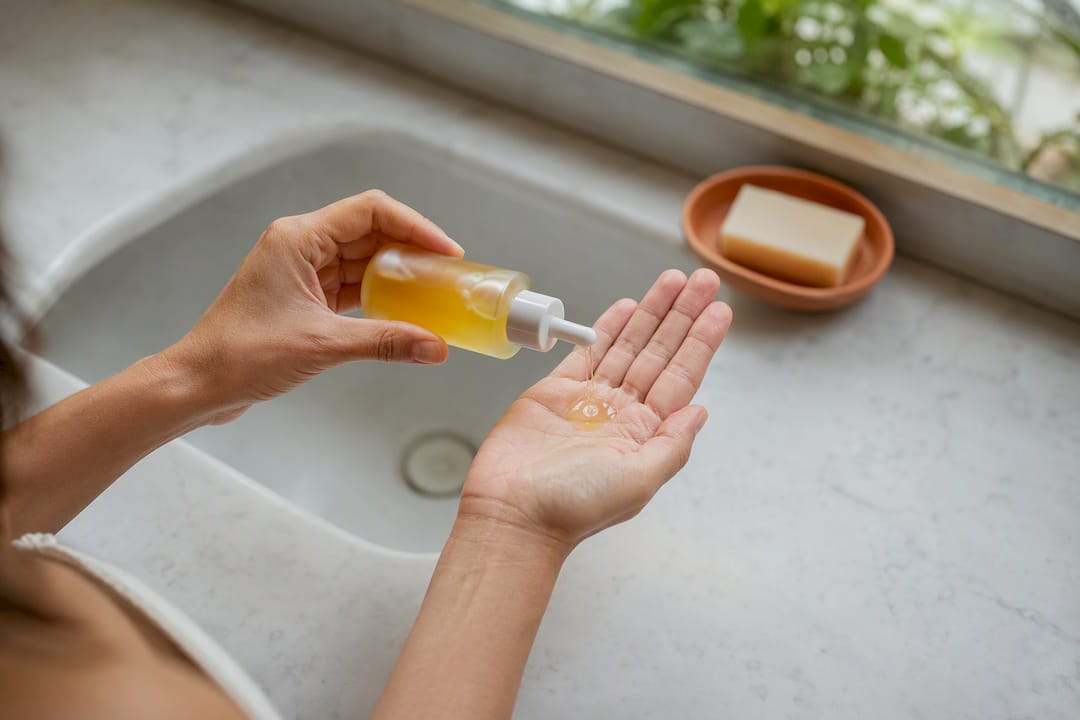 Hands pouring cleansing oil in skincare routine