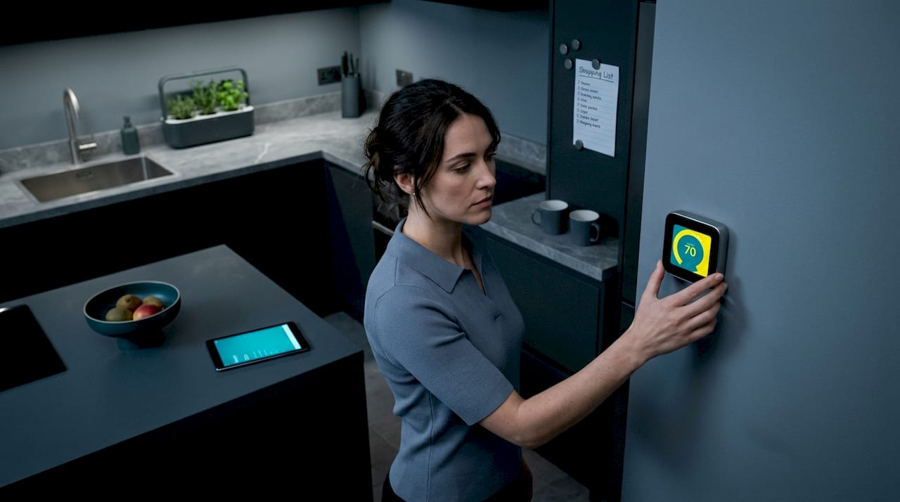 Woman set smart thermostat in bright kitchen