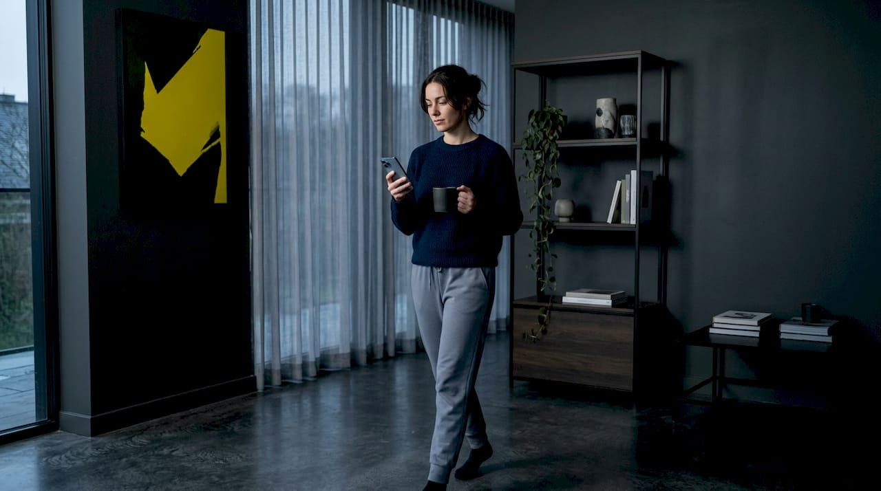 Woman moves around living room checking phone signal