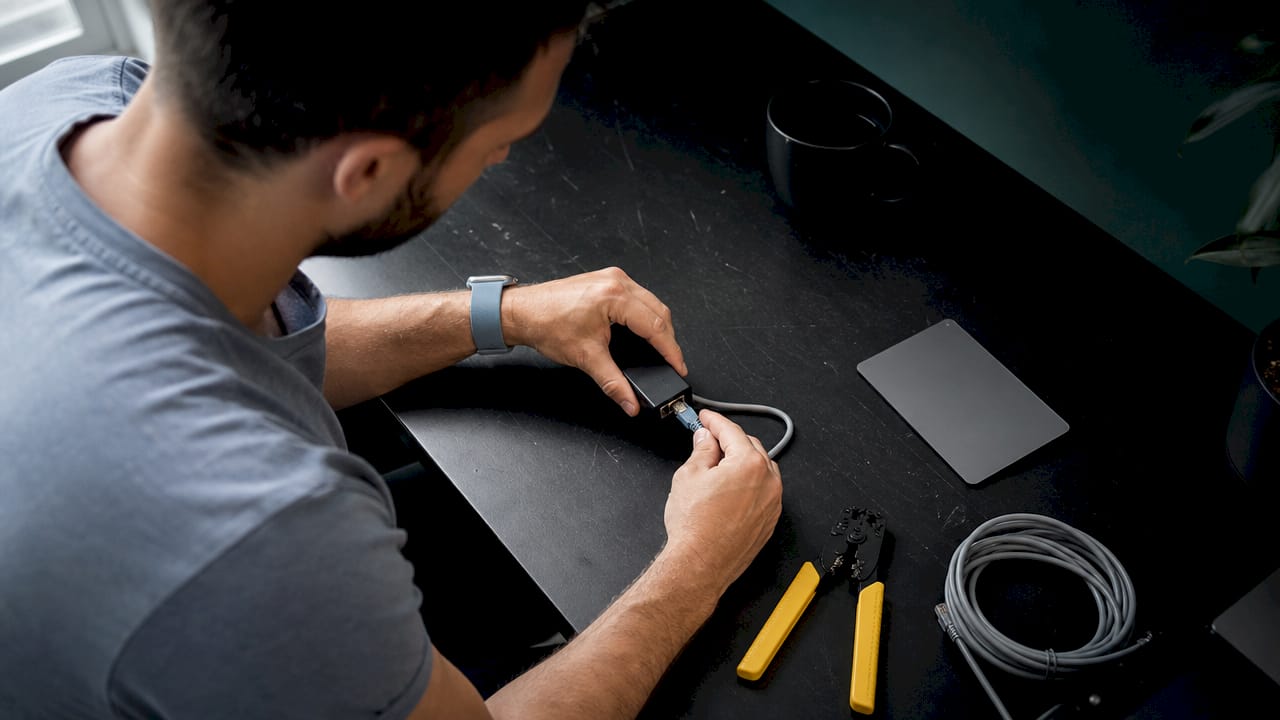Hands connecting Ethernet cable to PoE injector