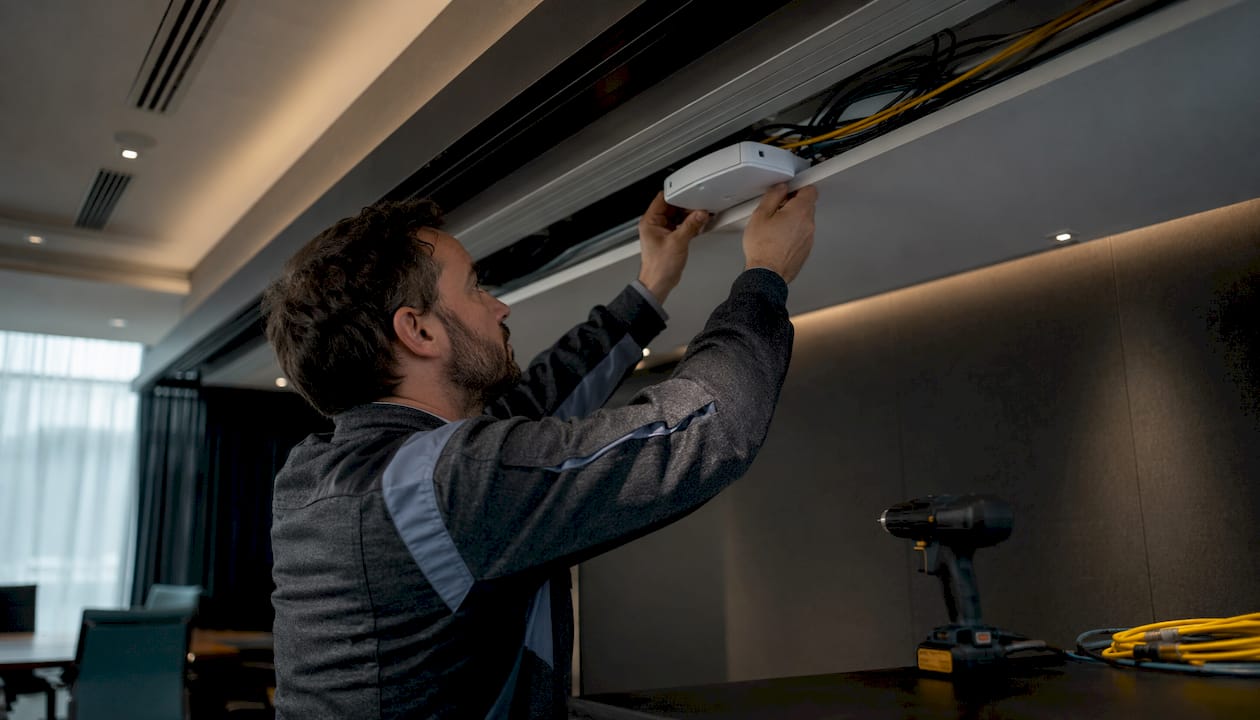Hands installing wifi access point in office ceiling