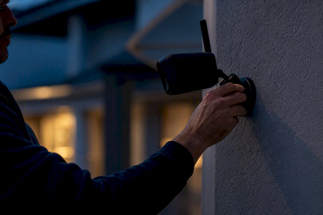 Hand attaching wireless security camera to wall bracket