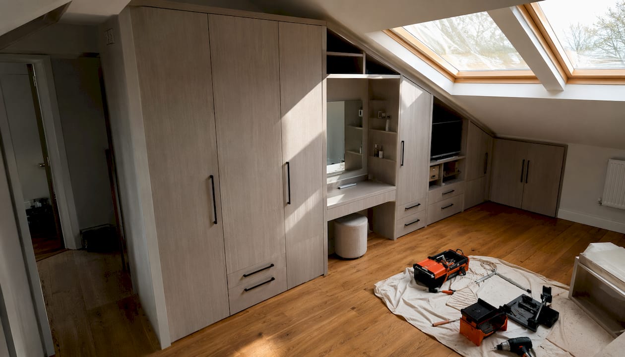 Loft bedroom with bespoke fitted wardrobe under sloped ceiling