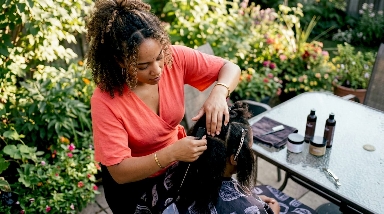 Stylist shampooing client's hair before braiding
