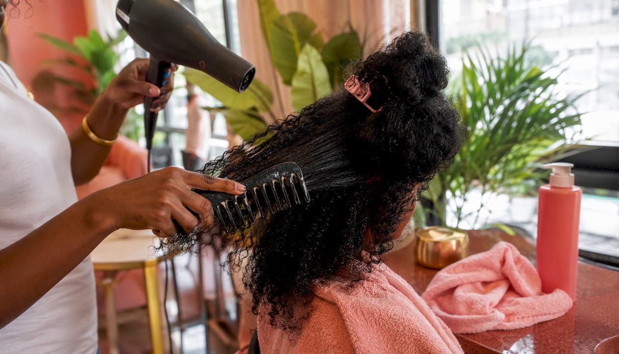 Hands detangling natural hair with blow dryer