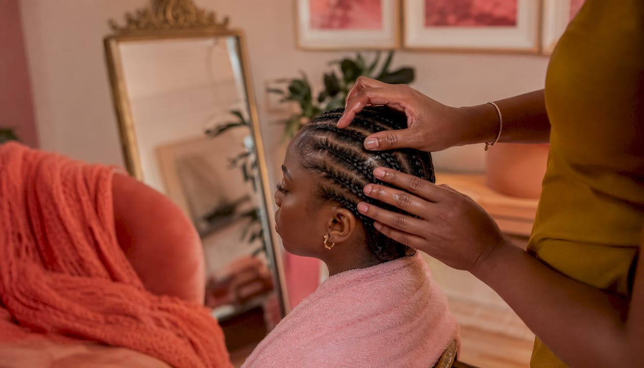 Hands moisturizing scalp between cornrows at home