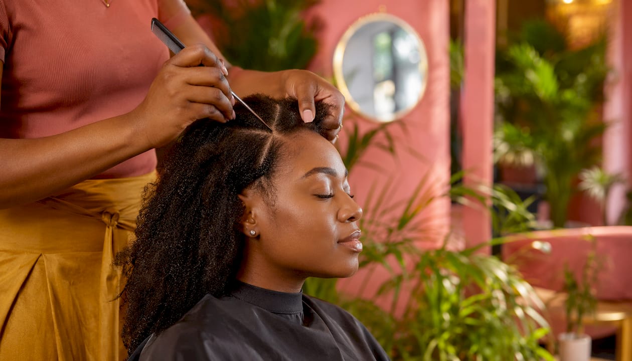 Stylist preparing hair with rat-tail comb in salon