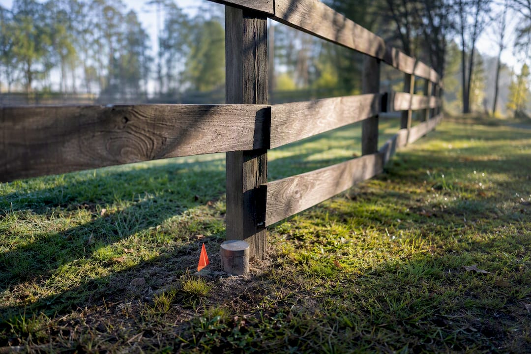 Fence crossing a property survey boundary marker