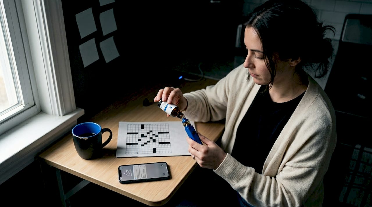 Woman refilling vape pen at kitchen desk