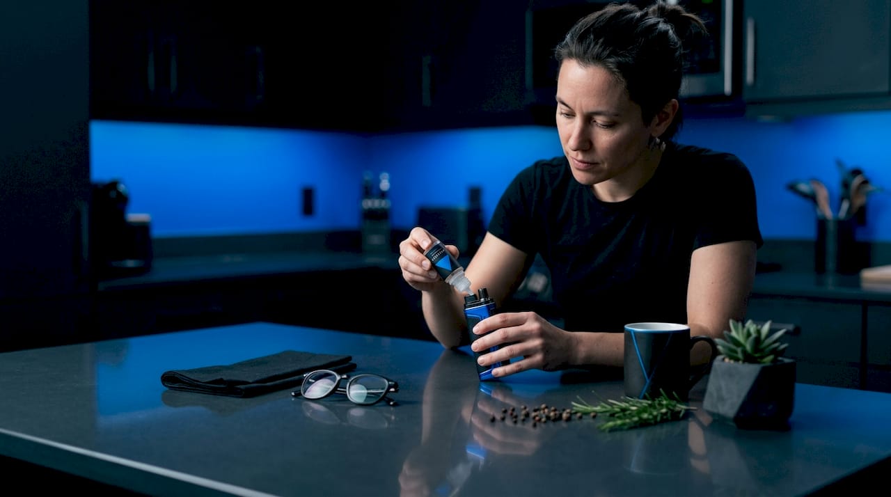 Adult refilling refillable vape device at kitchen table