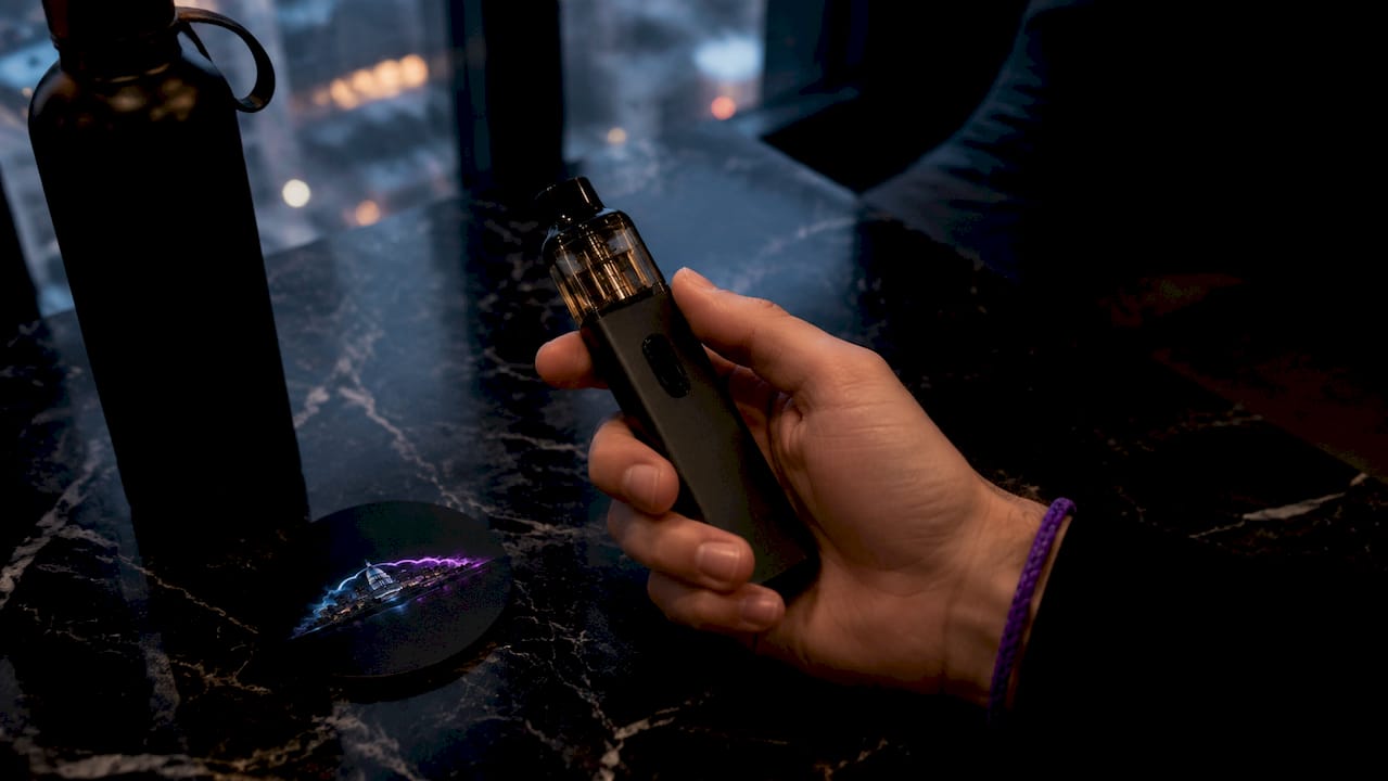 Close-up of hand holding high puff vape device at desk