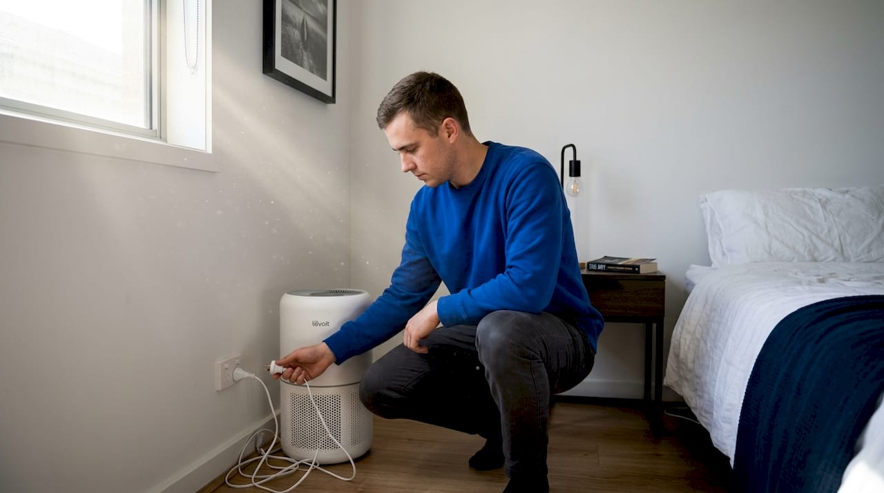 Man setting up air purifier in bedroom