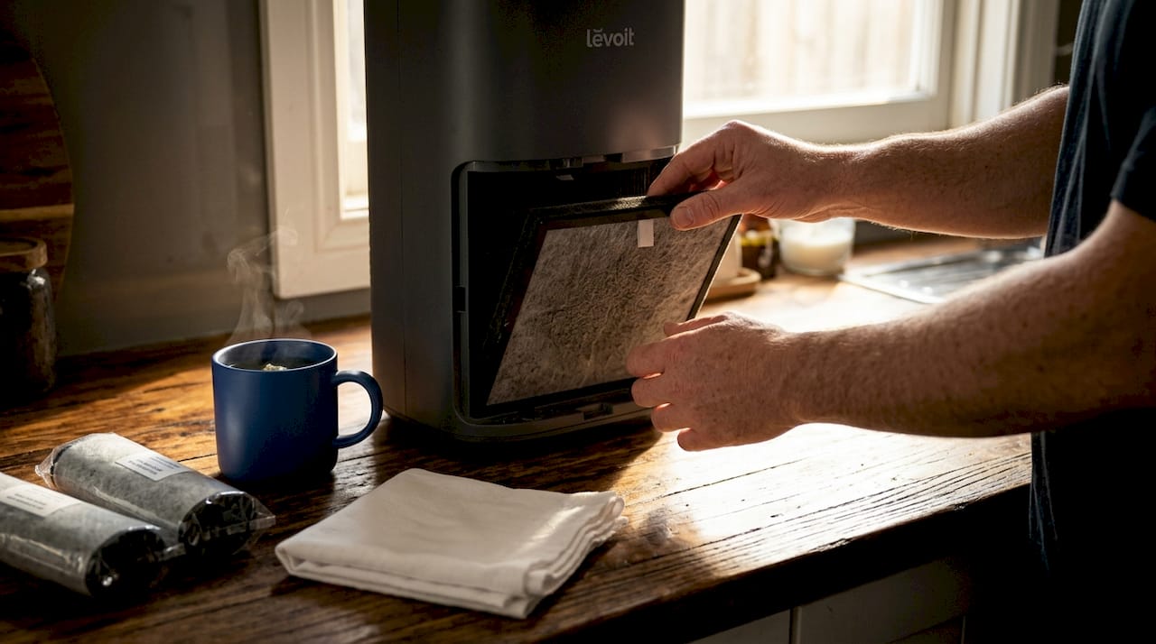 Hands replacing air purifier carbon filter