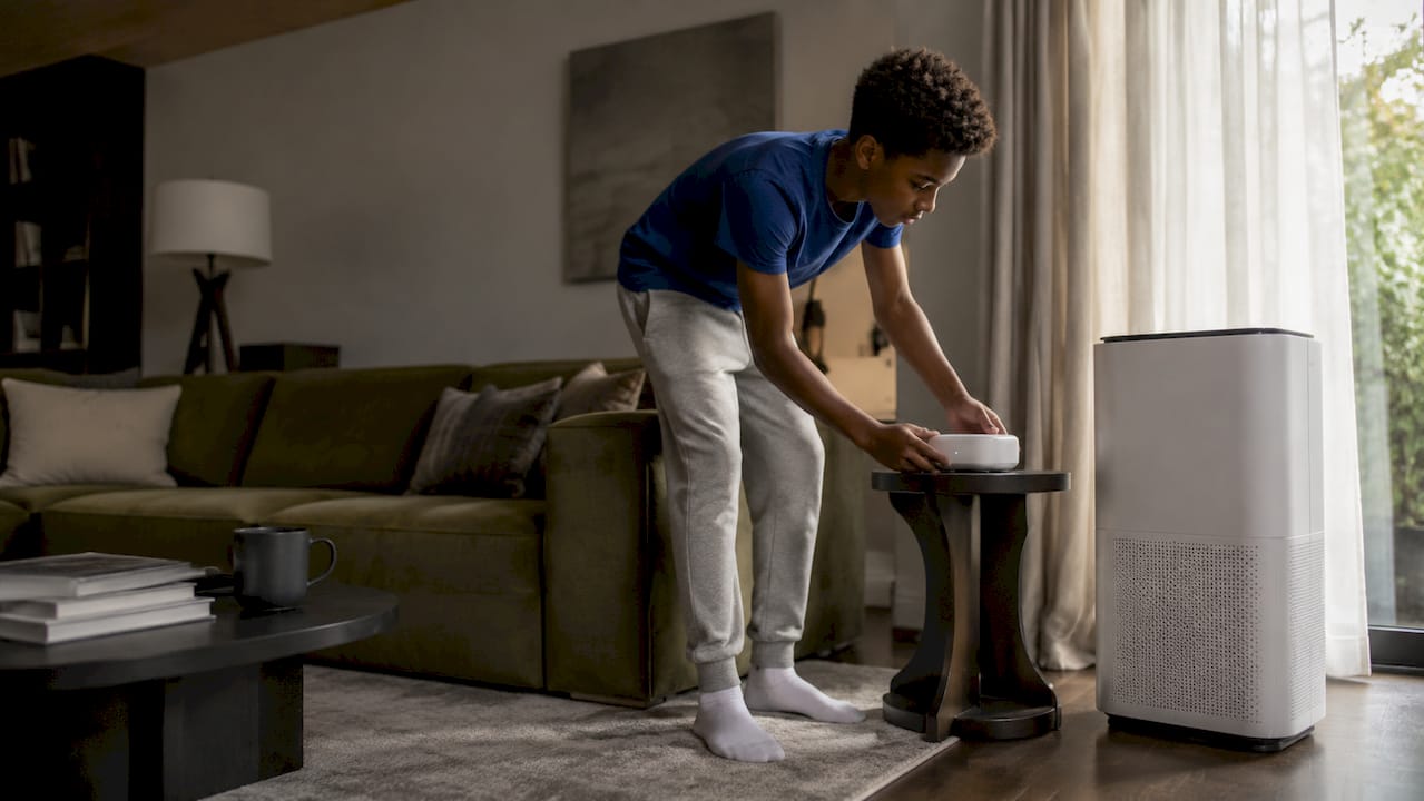 Teen placing air monitor away from purifier