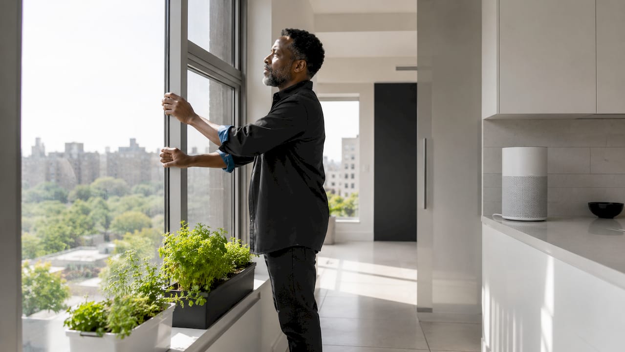 Man closing apartment window to block allergens