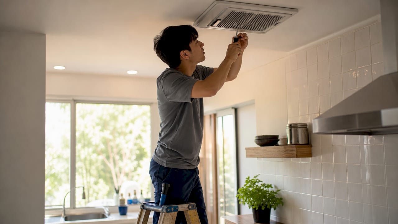 Technician inspecting bathroom exhaust vent
