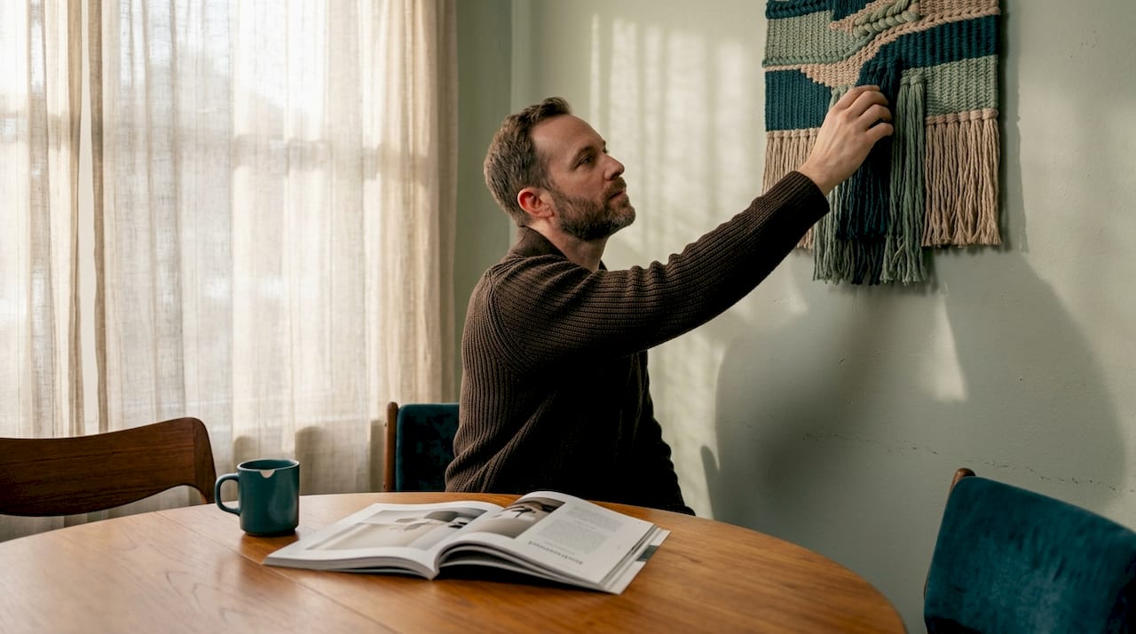 Man interacting with textile wall art at home