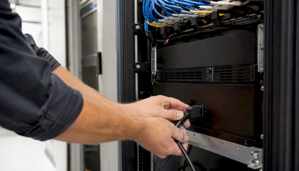 Hands connecting UPS backup power cable