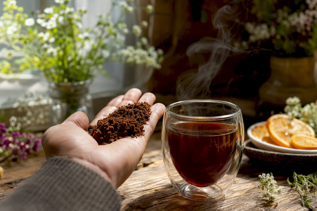 Close-up of coffee grounds and steaming cup with floral aroma