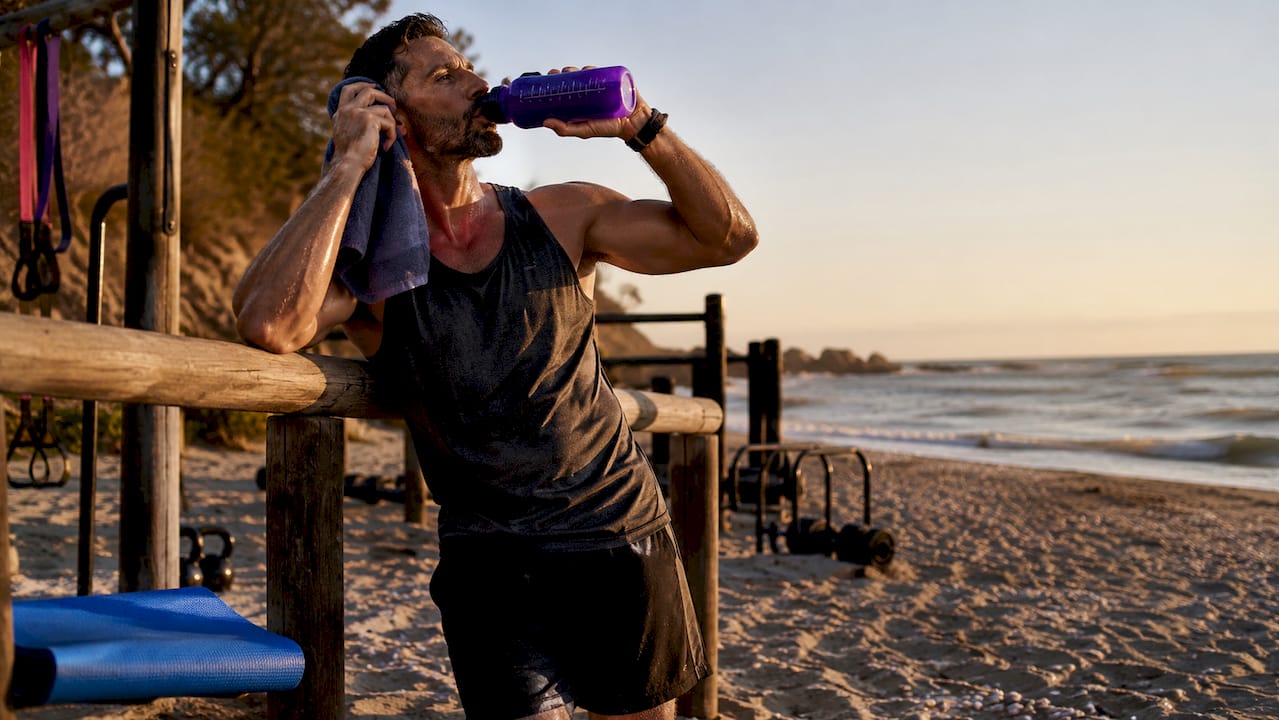 Athletic man hydrating outdoors after workout
