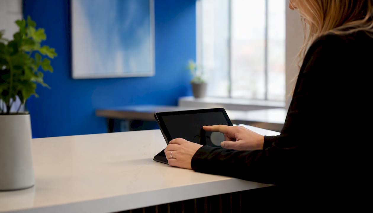 Hands logging patient wait times at clinic desk