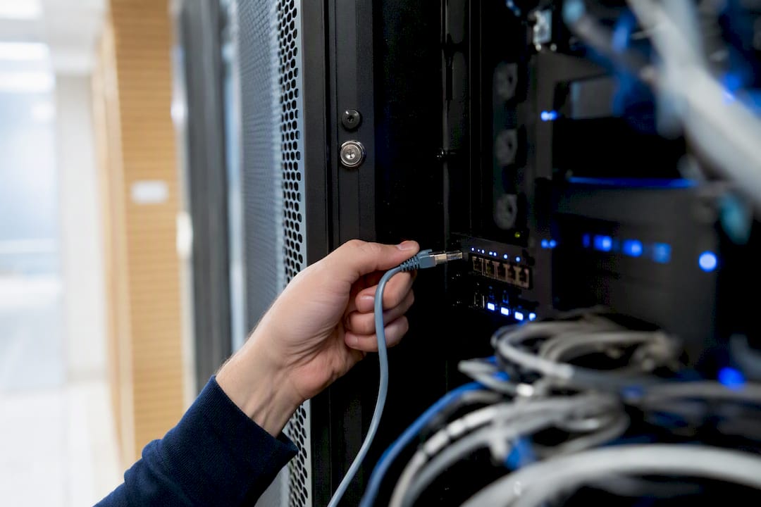 Hands connecting secured network cable in server room
