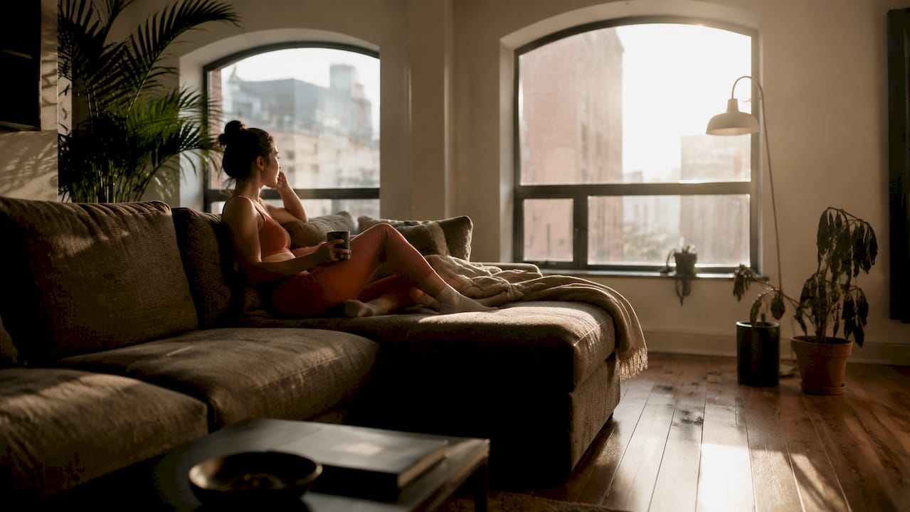 Crowded living room with bulky oversized sofa blocking sunlight