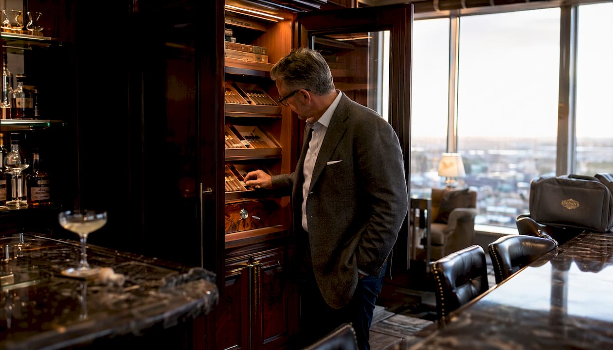 Man inspecting large built-in humidor in home bar