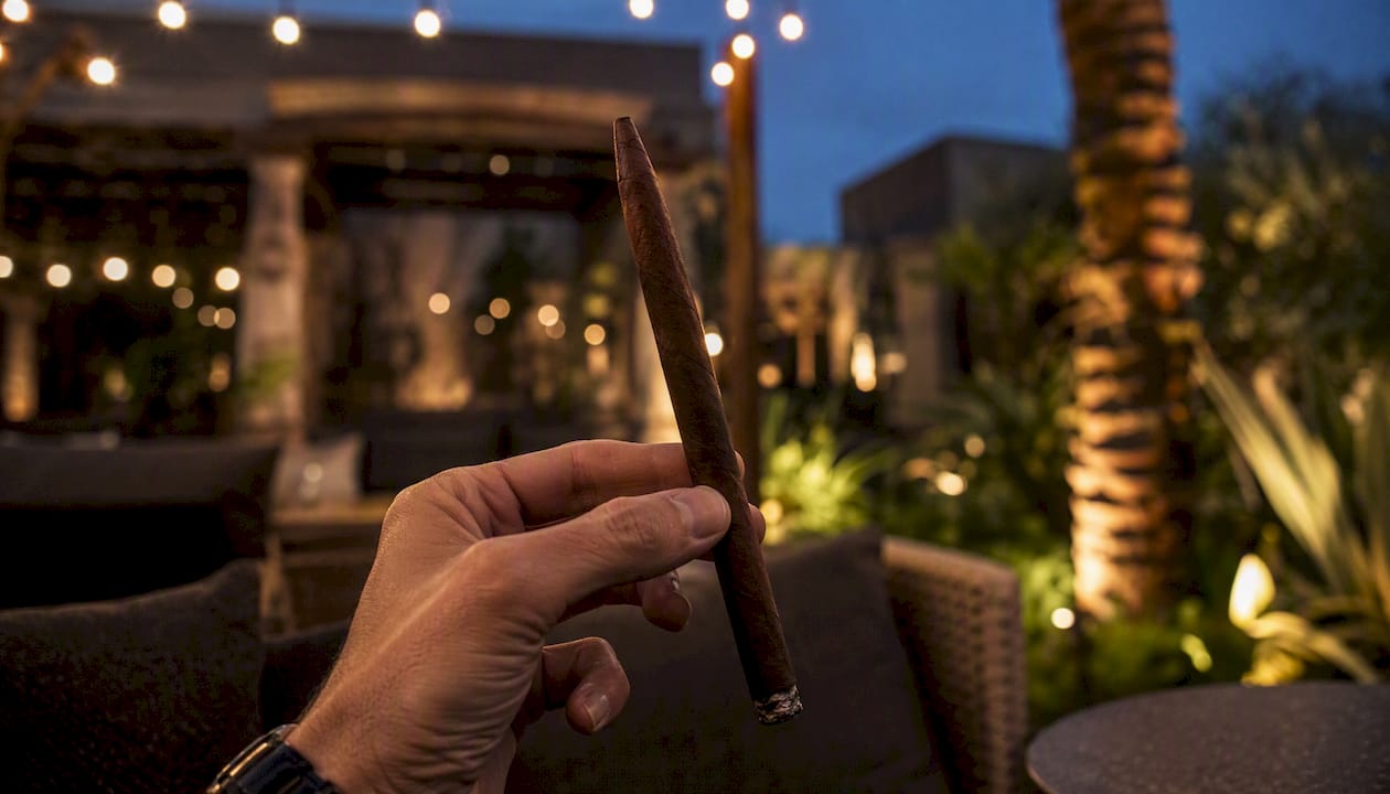 Hand holding a slender, tapered Lancero cigar