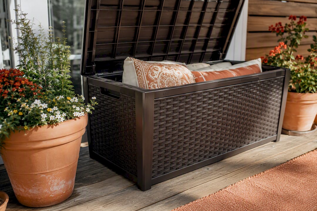 Closed resin deck box on patio with cushions nearby
