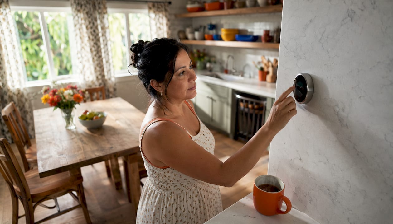 Woman adjusting smart thermostat in living room