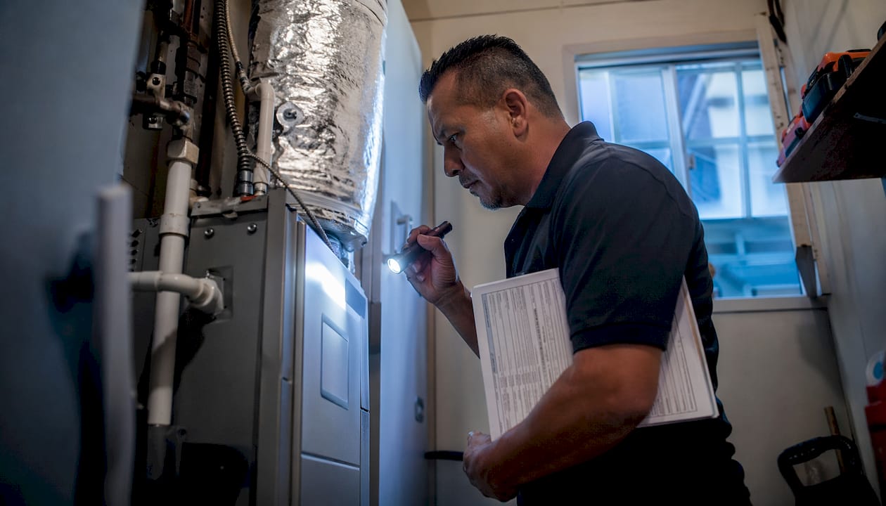 Man inspecting home furnace with checklist