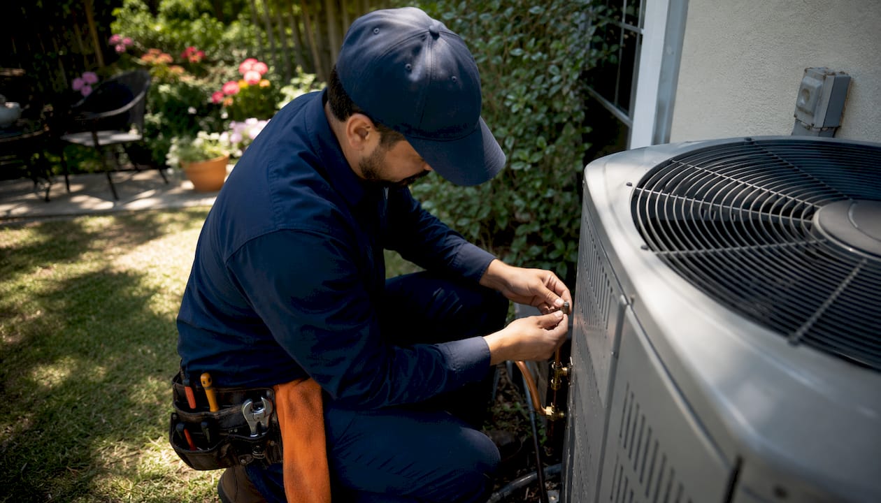 Technician tightening HVAC Schrader valve outdoors