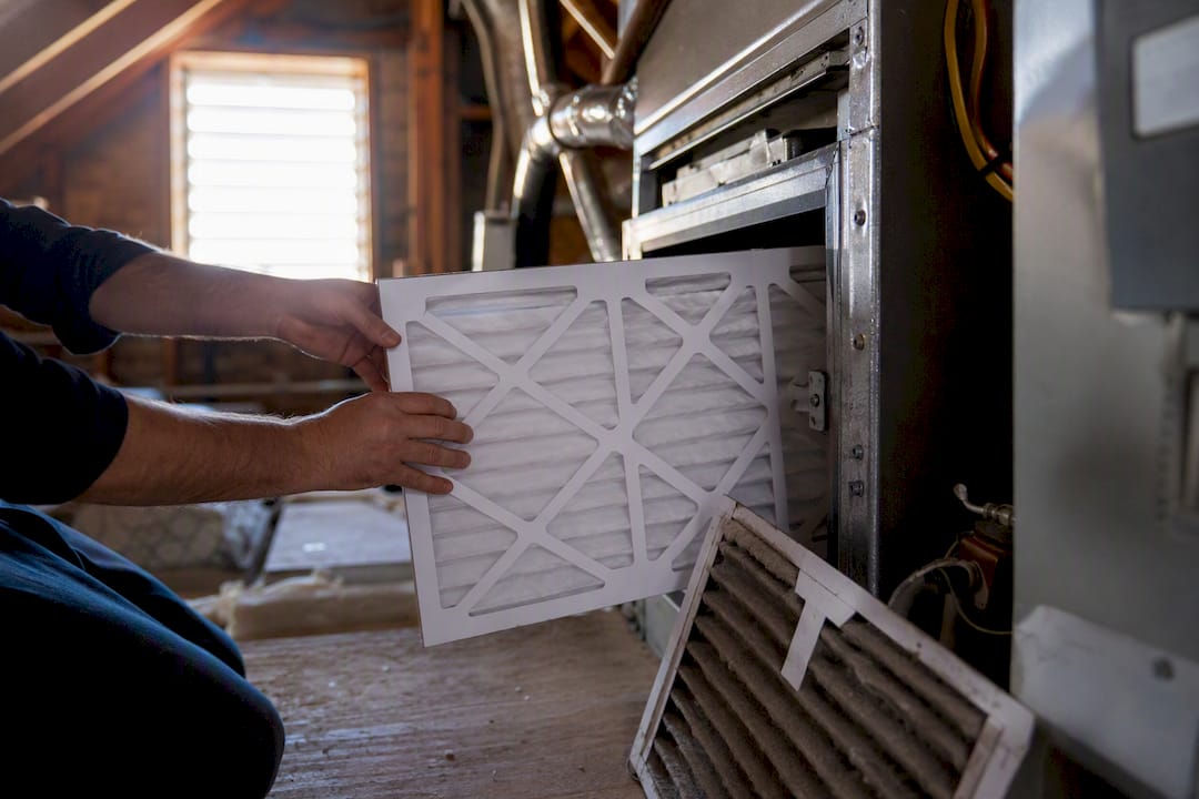 Hands installing air filter in home HVAC