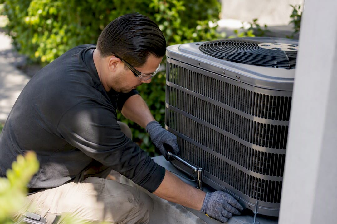 Technician adjusting outdoor AC unit hardware
